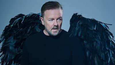 Ricky Gervais, wearing a pair of black angel wings