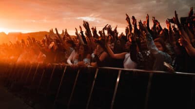 A crowd celebrates at a music festival as the sun sets