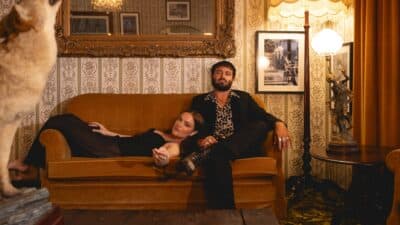 Angus and Julia Stone sit on a sofa in their living room