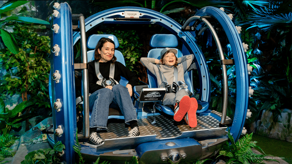 A woman and a child pose for a photo in the gyrosphere vehicle made famous by the Jurassic World films at Jurassic World: The Experience, in Manchester