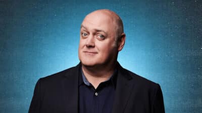 Dara Ó Briain raises an eyebrow against a dark background