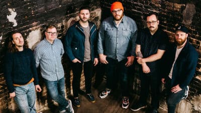 The band The Wonder Years line up against a brick wall