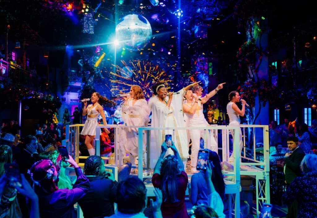 The cast of Mamma Mia! The Party dancing on stage