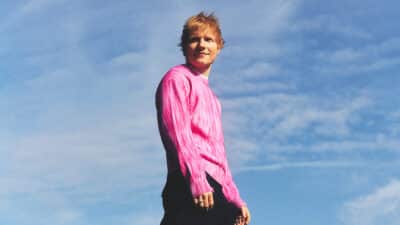 Ed Sheeran standing against a backdrop of of clear skies
