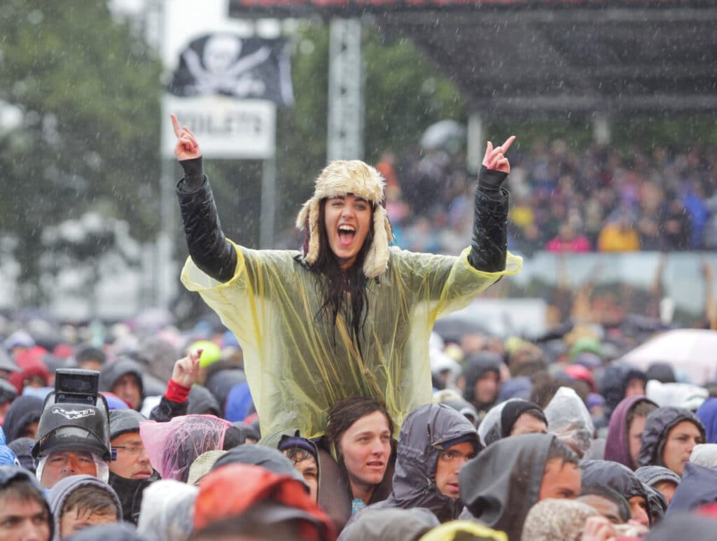 Festival goers stand in the rain during day three of the Isle of Wight Festival