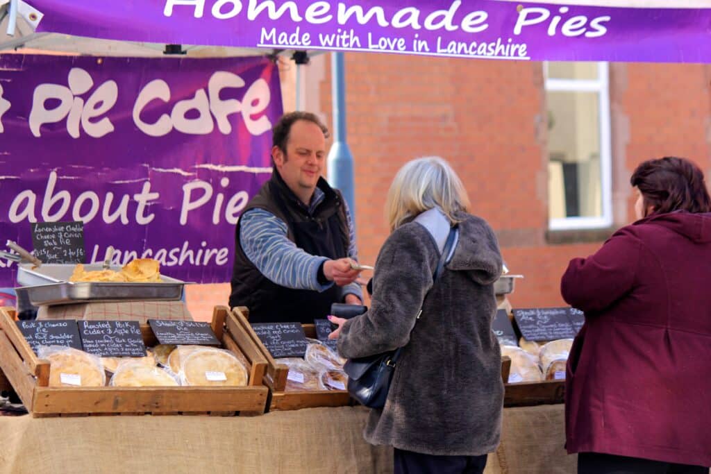 Woman buying pies at a weekend farmer's market held in Prestwich, North Manchester