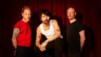 Press shot showing the three members of Biffy Clyro, who are touring next year, against a red curtain backdrop