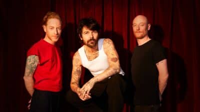 Press shot showing the three members of Biffy Clyro, who are touring next year, against a red curtain backdrop