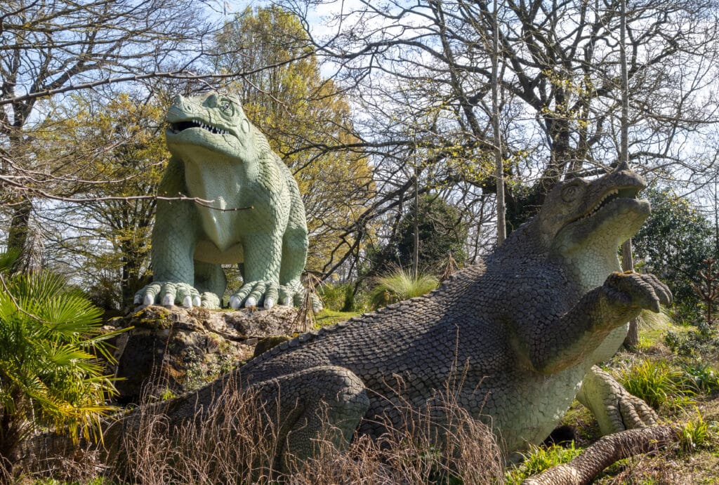 Two historic and famous Iguanodon dinosaur sculptures on an island in the public Crystal Palace Park in South East London