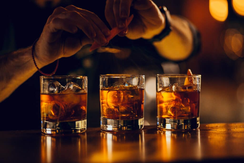Hand making three rum cocktails on the bar