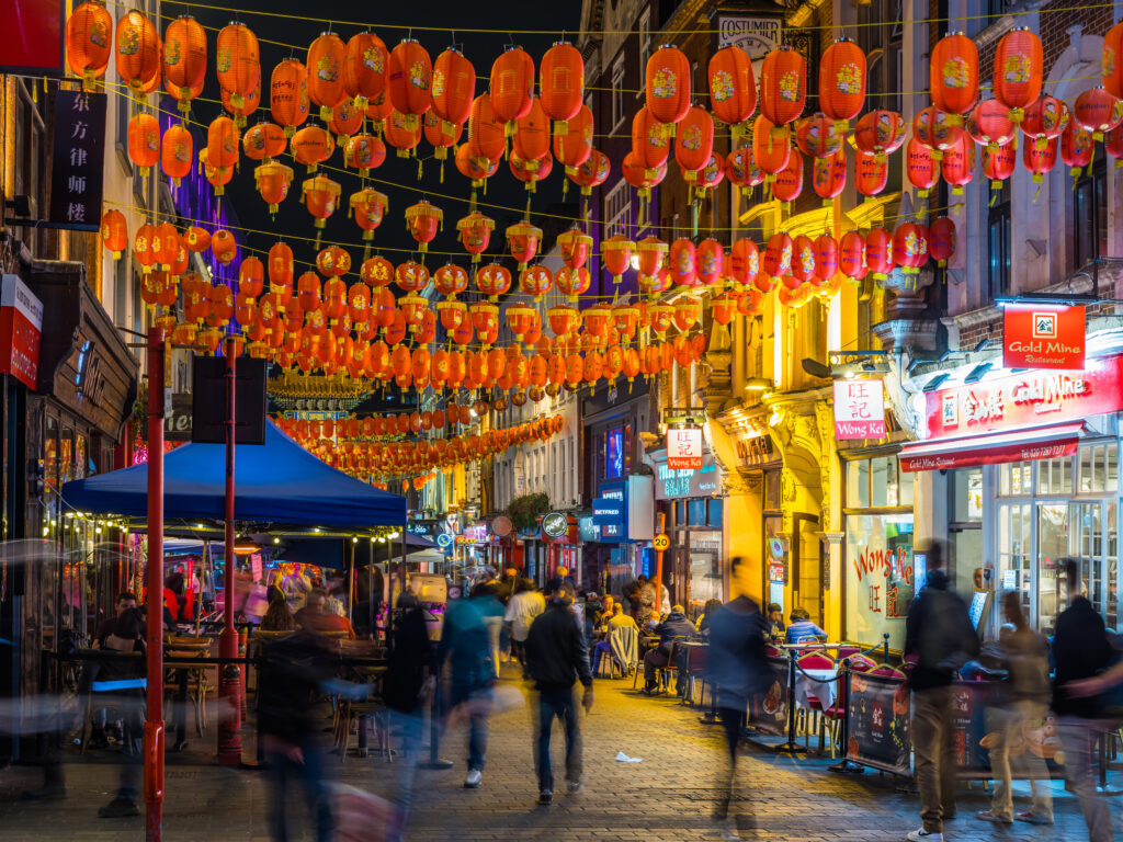 Crowds of people enjoying the warm summer night in the busy pedestrianised streets of Chinatown, London