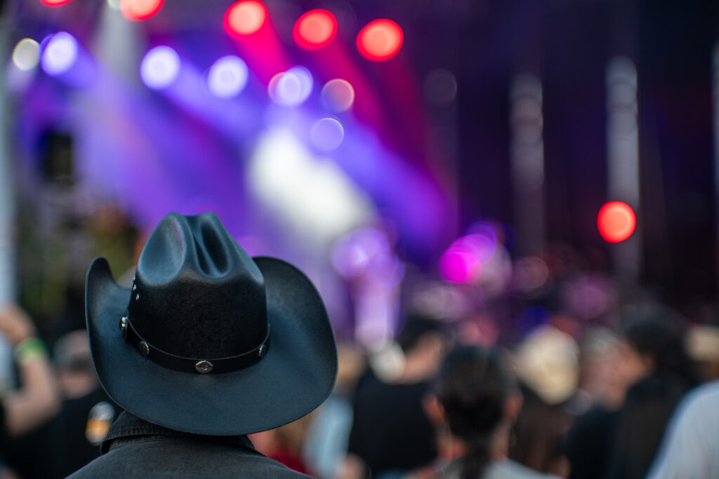 A man wearing a black cowboy hat at a country music show