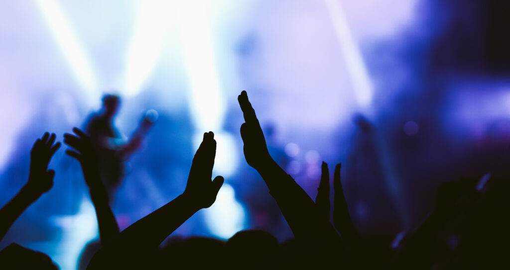 Crowd at a concert, stage lights and hands in the air