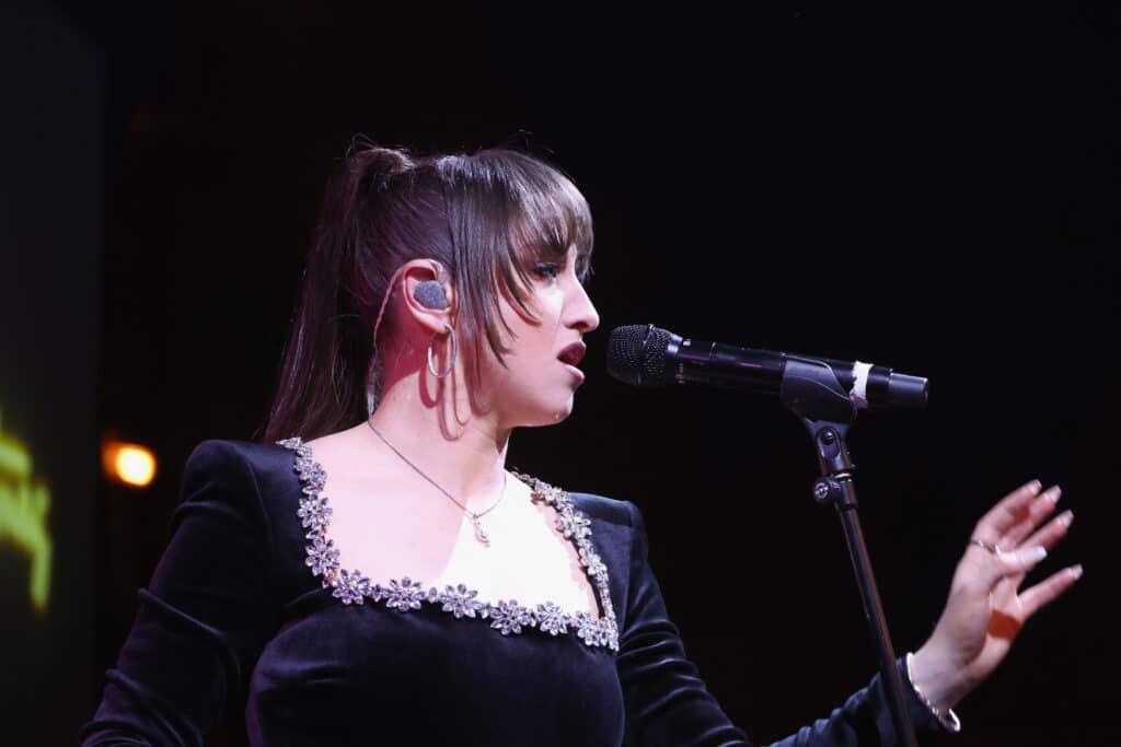 Sydnie Christmas singing into a microphone during a live performance