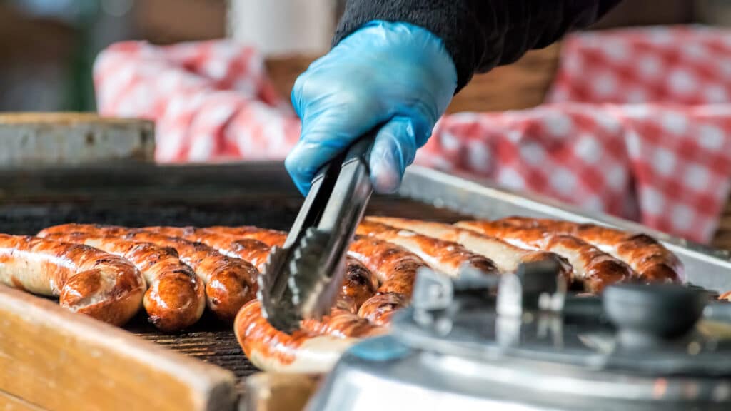 Take away sausage being grilled at public food market stand