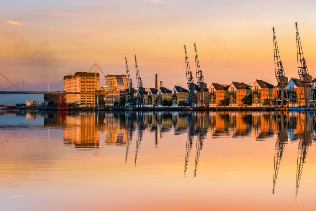 Royal Docks in London at sunset with dockside cranes and waterfront terraced houses