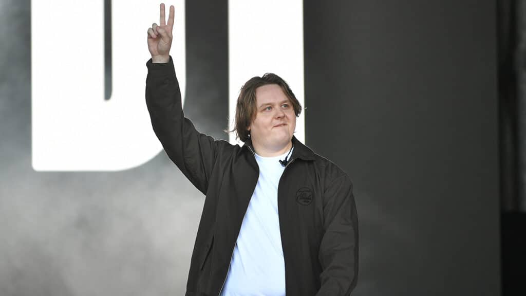 Lewis Capaldi holds up two fingers in a peace sign on stage