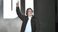 Lewis Capaldi holds up two fingers in a peace sign on stage