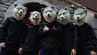MAN WITH A MISSION stand in front of a brick wall, all wearing wolf masks