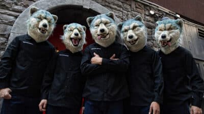 MAN WITH A MISSION stand in front of a brick wall, all wearing wolf masks