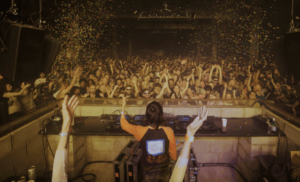A DJ playing in front of a crowd as confetti is blasted into the air