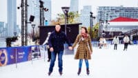 A couple hold hands as they skate at Glide at Battersea Power Station