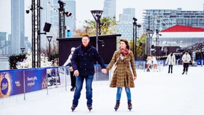 A couple hold hands as they skate at Glide at Battersea Power Station