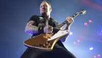 Michael Poulsen of Volbeat towers over the camera, playing a guitar