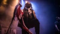 Benji Webbe of Skindred Performs on stage holding a tattered Union Jack flag