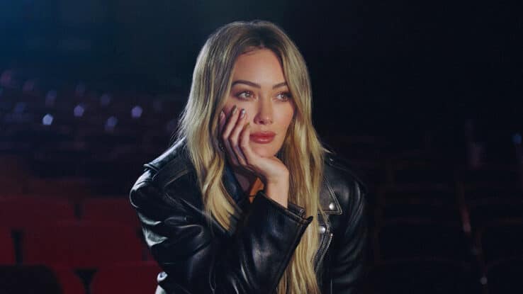 Hilary Duff holds her head in her hand