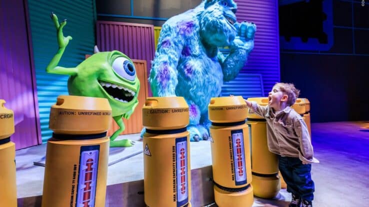 child posing with Mike and Sully at Mundo Pixar experience