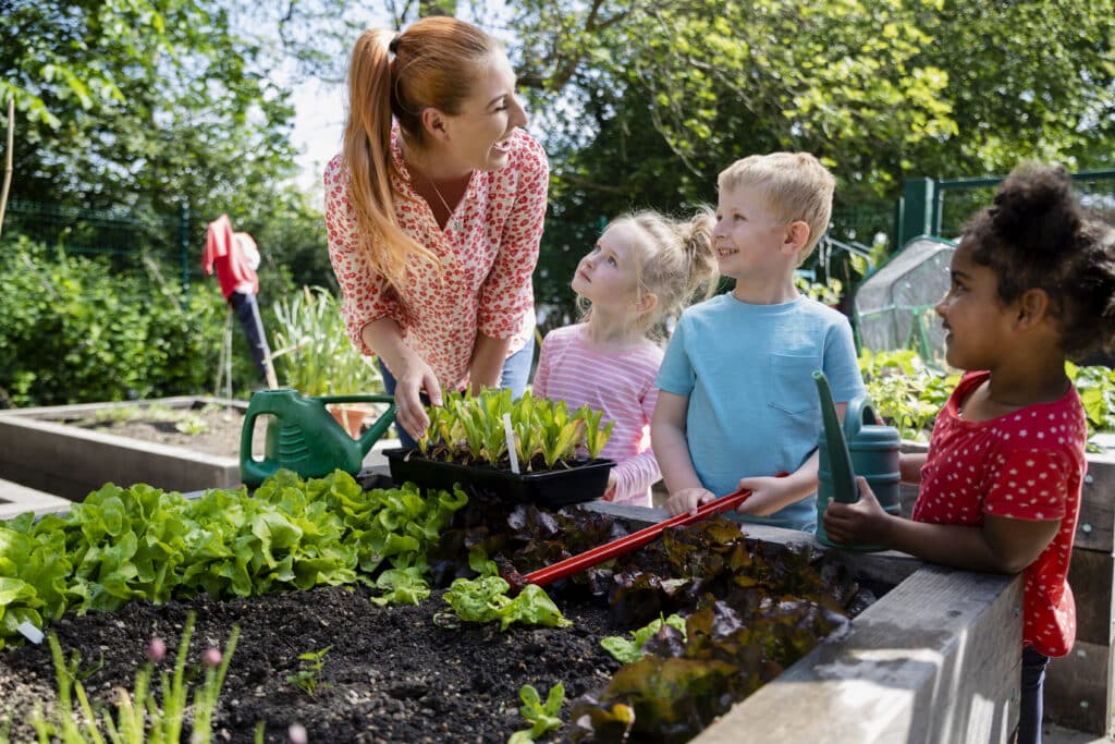 A woman gardening in an allotment with three children