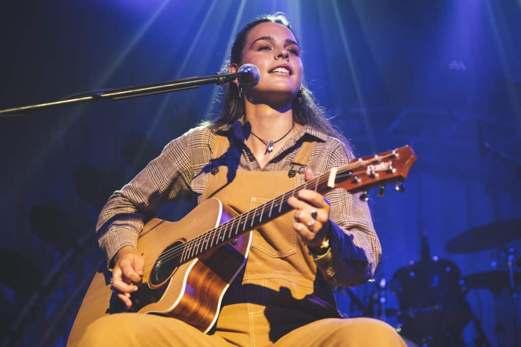 Australian singer-songwriter Steph Strings performing live on stage with a guitar and a microphone