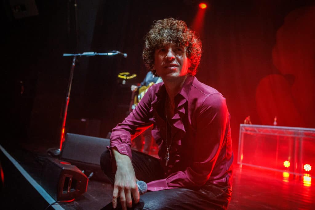 Luke Pritchard from The Kooks sits on stage in 2026