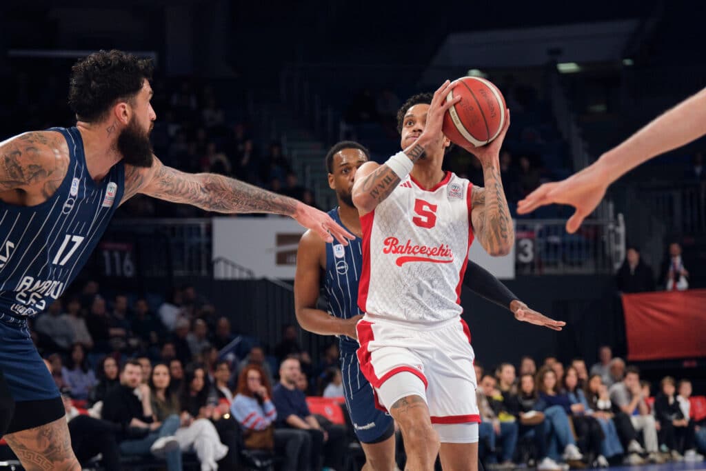 A male basketball player about to take a shot surrounded by other players