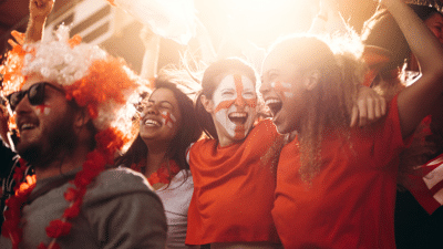 England soccer supporters cheering in stands. Women with England flag painted on their faces having fun in fan zone at stadium.