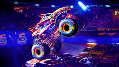 A monster truck jumps a car in Hot Wheels Monster Trucks Live Colour Bash