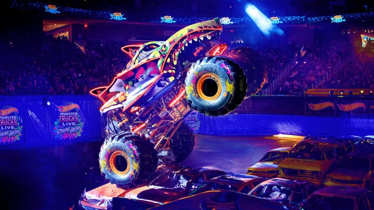 A monster truck jumps a car in Hot Wheels Monster Trucks Live Colour Bash