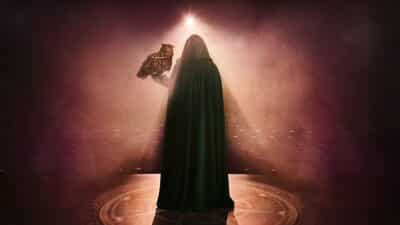 A hooded figure holds an owl