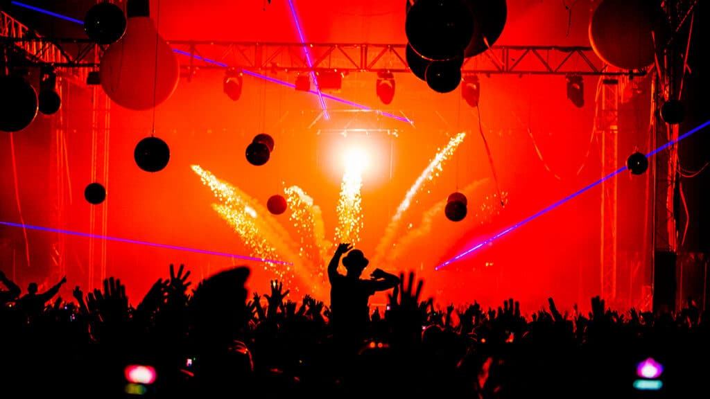 Hands in the air silhouette payrotechnics at edm party festival.